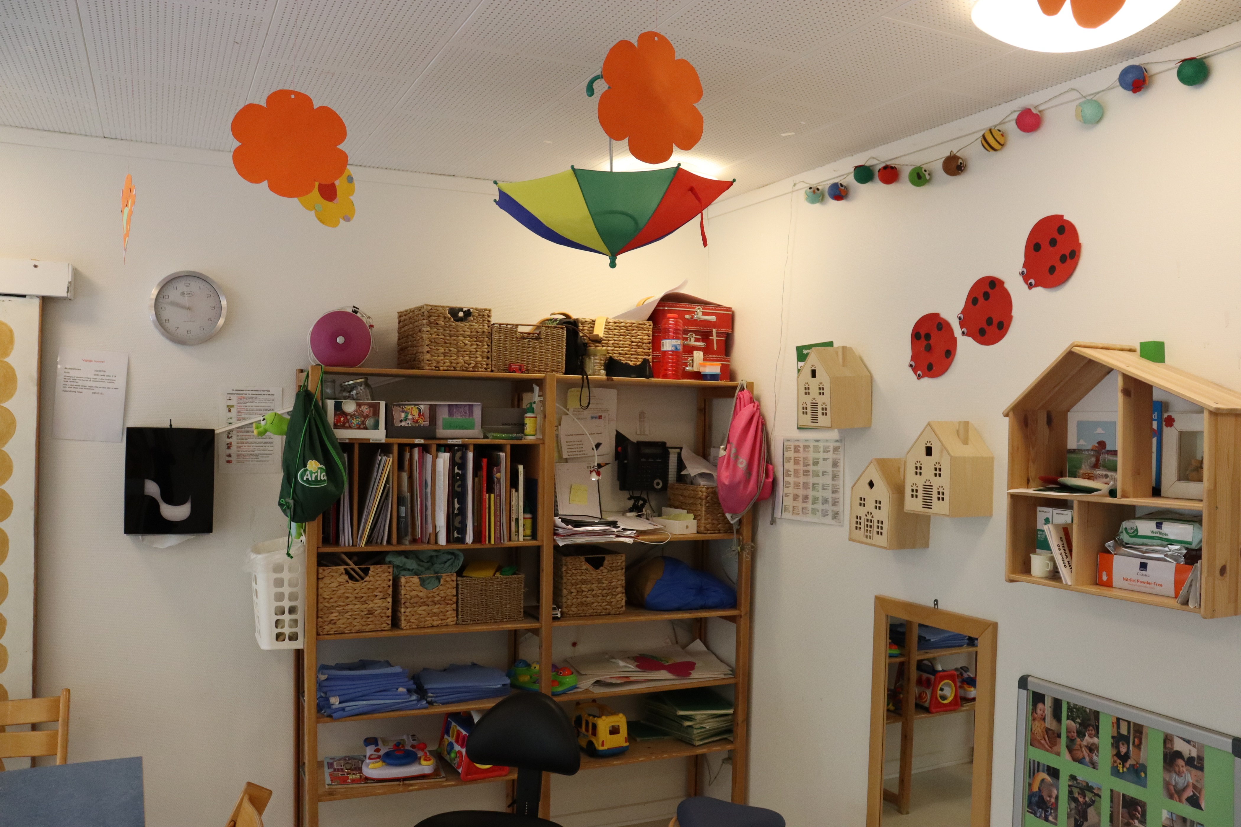 Vuggestuens stue med masser af ting på væggen og børnenes kreative ting, som hænger ned fra loftet