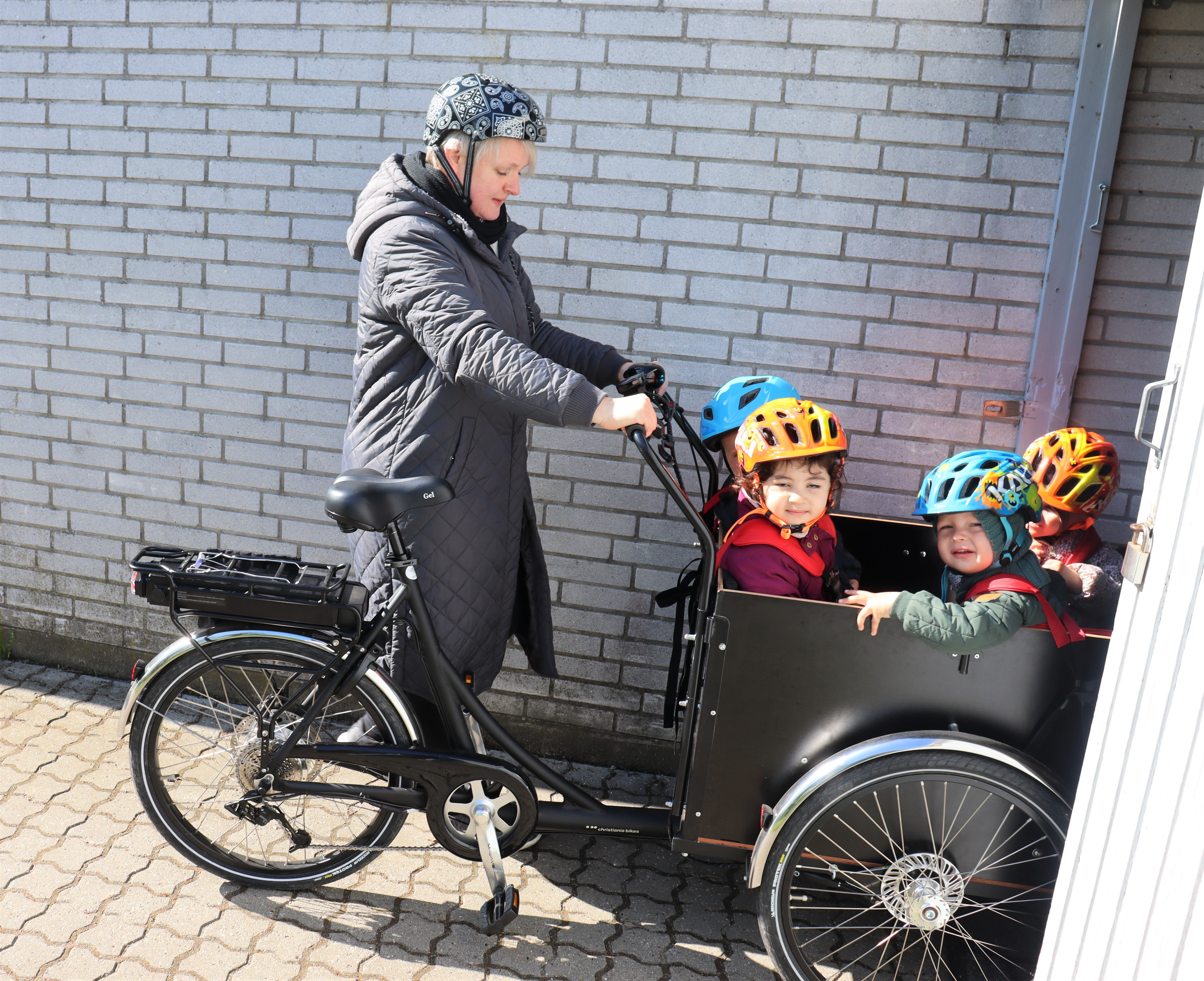 Pædagog cykler med børn i ladcykel