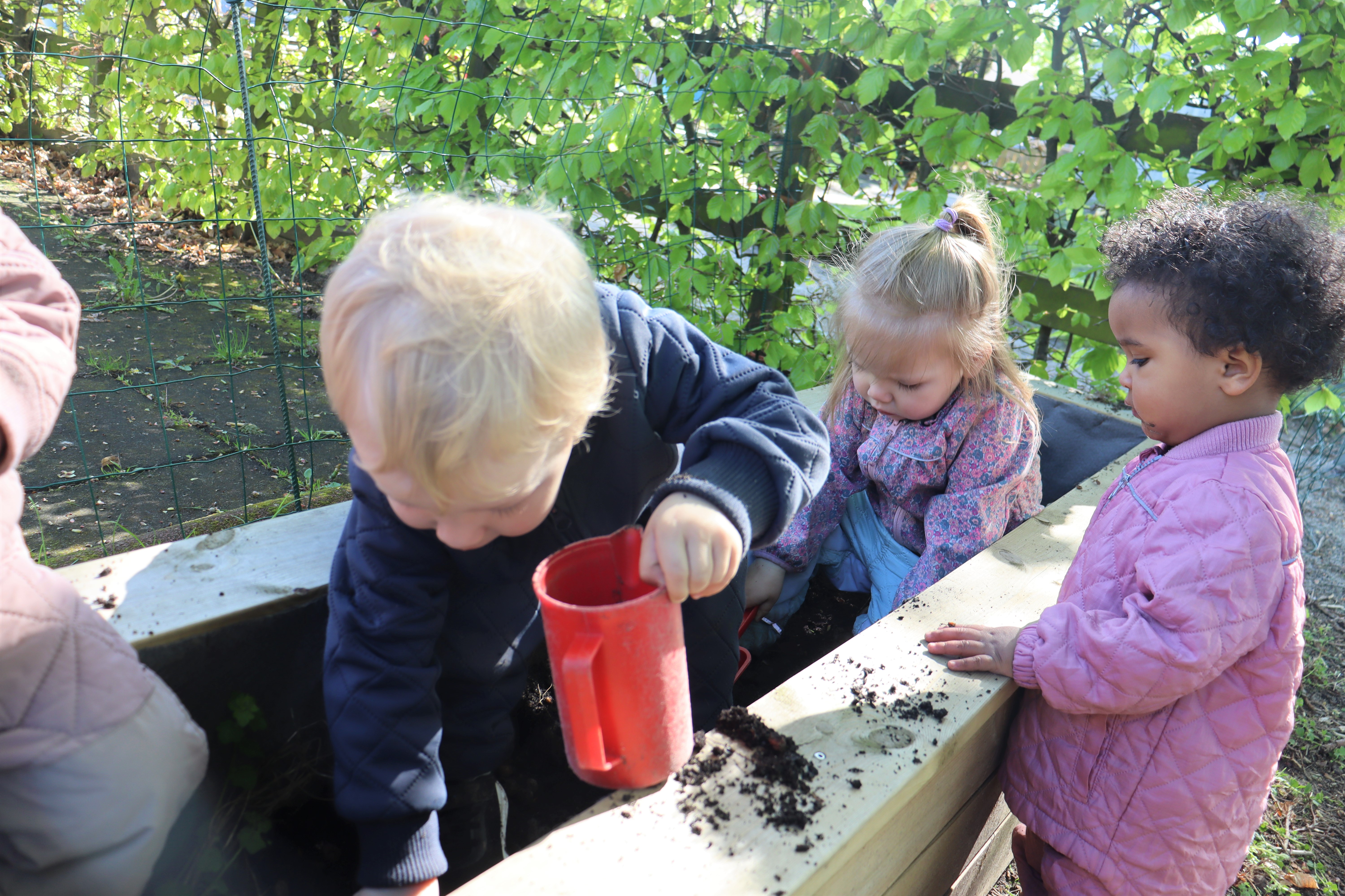 Børn leger med jord, spande og skovle