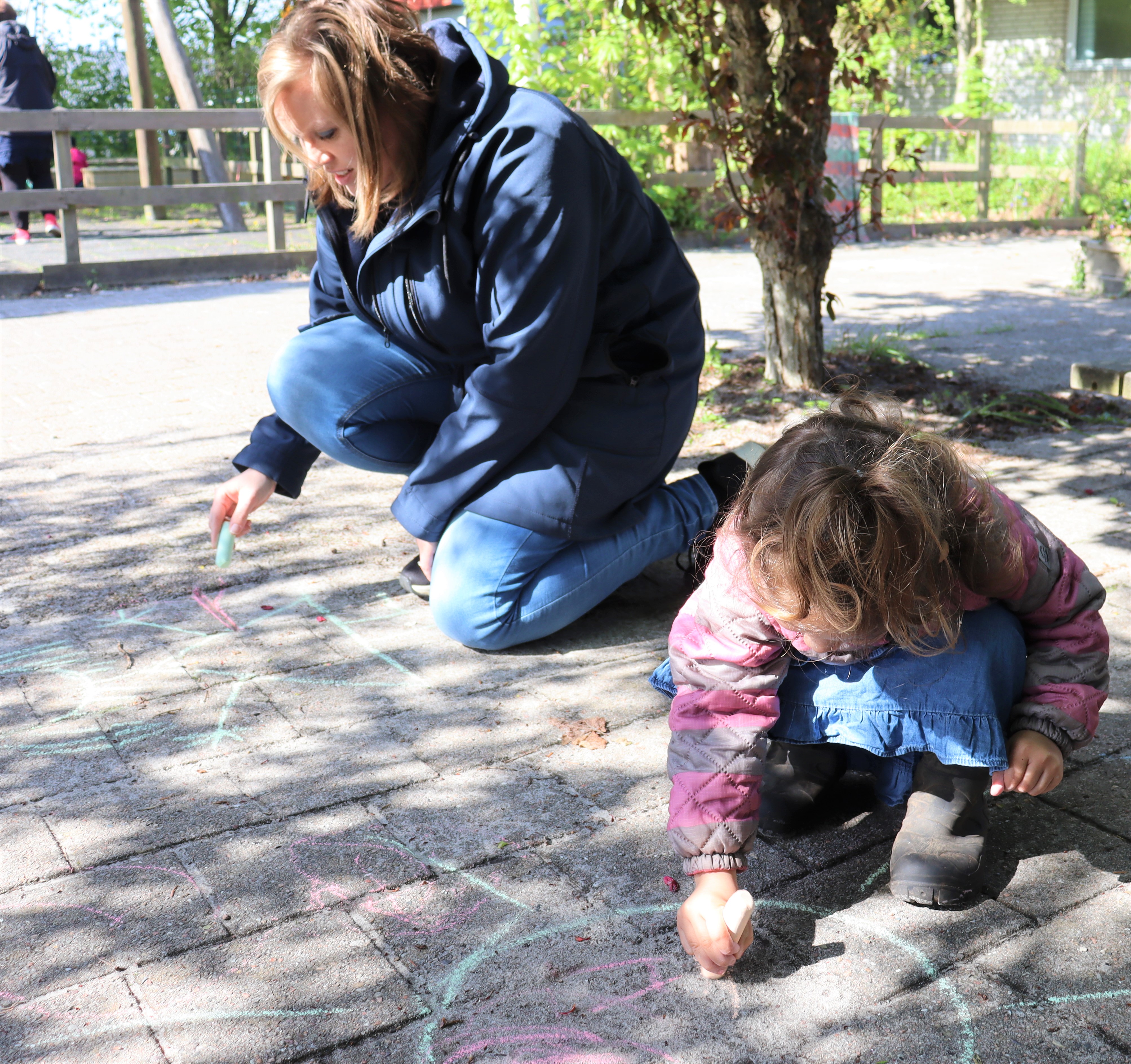 Pædagog tegner med kridt sammen med et barn